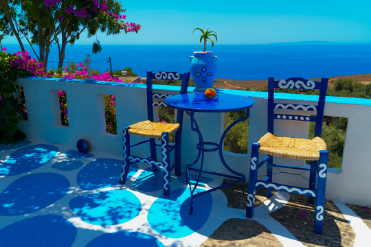 Zwei blaue St&uuml;hle an einem Tisch mit Blick &uuml;ber das Meer